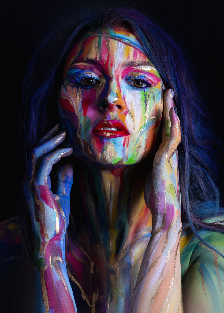 artystyczny portret kobiety z kolorową farbą na twarzy, ciemne tło