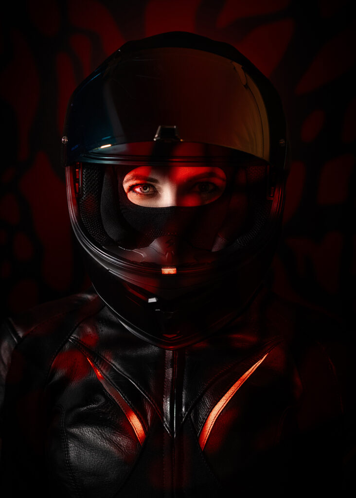 autoportret fotografki w kasku motocyklowym, czerwone światło, czarne tło