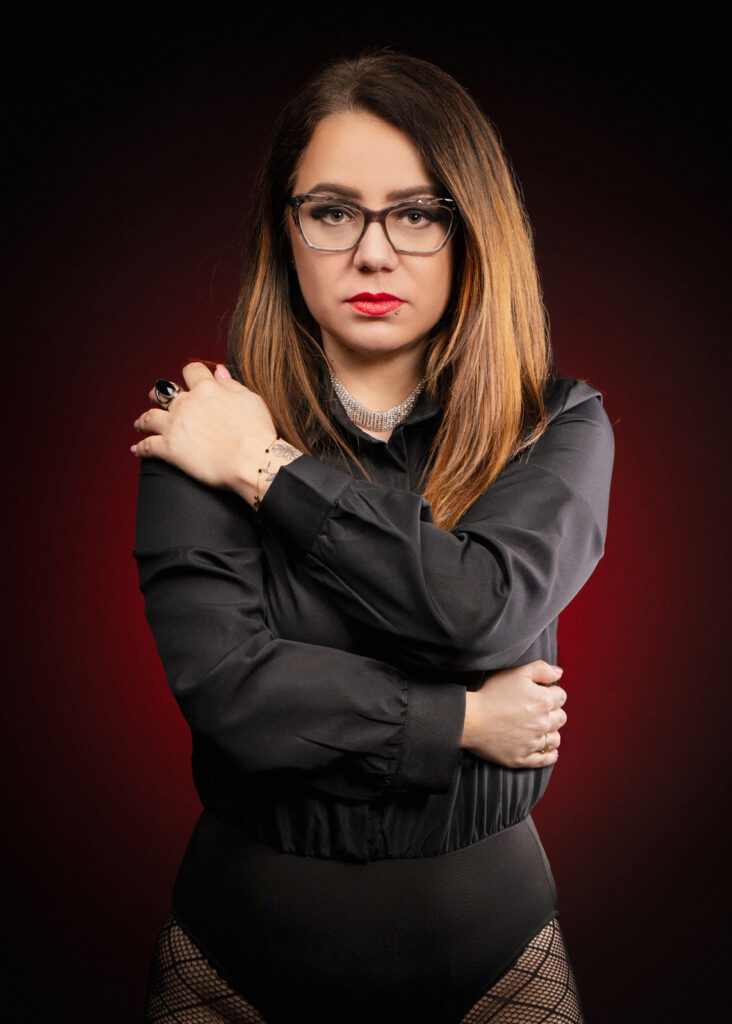 portret kobiety z minimalistycznym makijażem i czerwonym akcentem na szyi, jasne tło