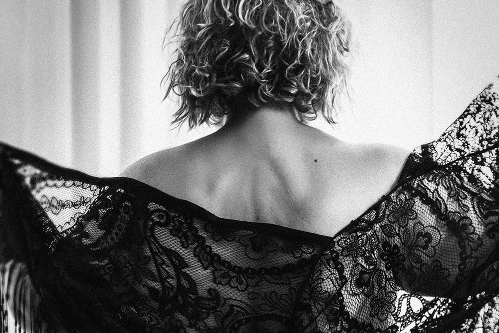 Czarno-biały sensualny portret Magdy od tyłu, z koronkową chustą odsłaniającą plecy.